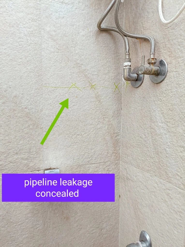 Beige-tiled bathroom with the concealed pipeline route marked in green with arrows