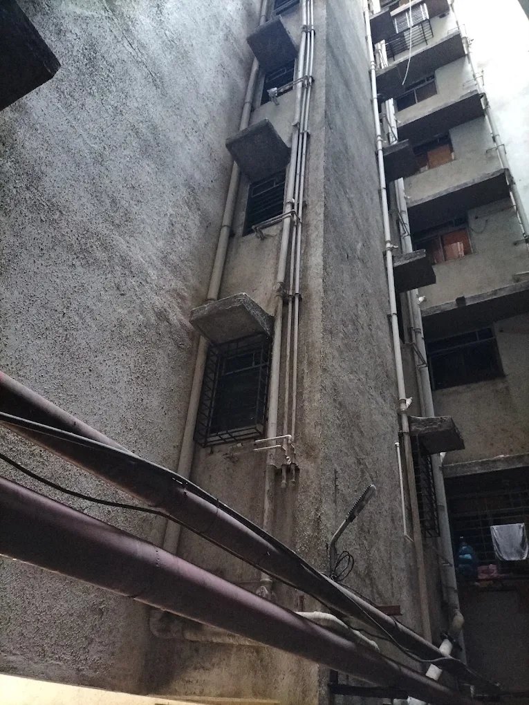 View up a residential building shaft at external riser and drain pipelines