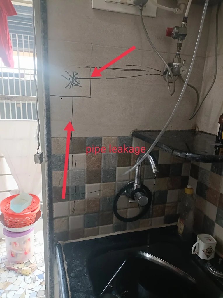 Kitchen wall with the leak path drawn in pen and red arrows labelled pipe leakage