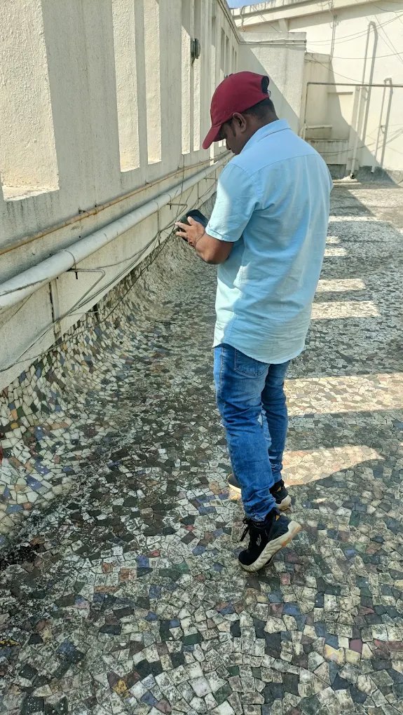 Technician surveying an open terrace and drain channel along a building parapet